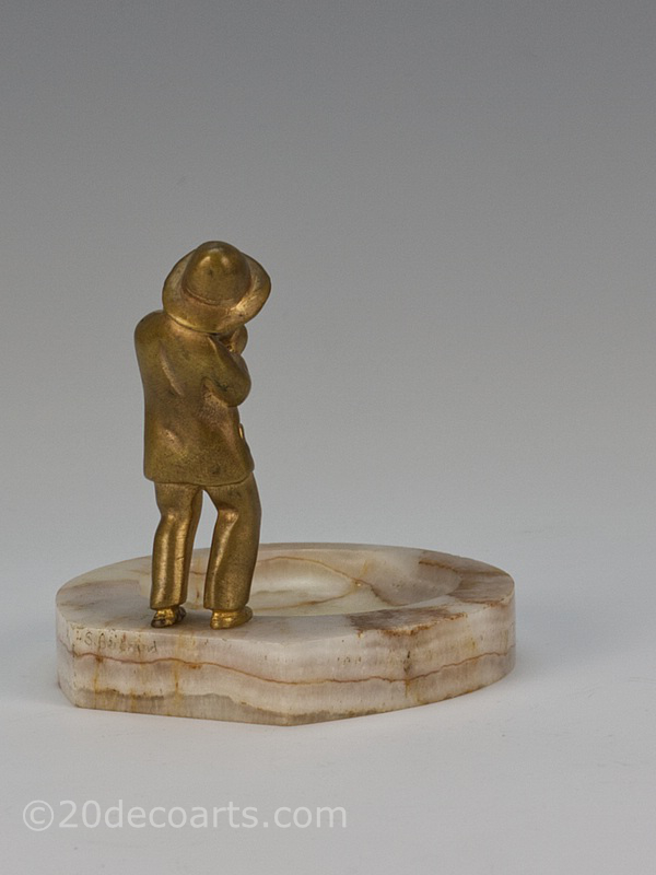  20th Century Decorative Arts |A gilded bronze figure vide-poche by Bertrand, France circa 1920s depicting a young boy in a suit lighting a cigarette mounted on a honey onyx base